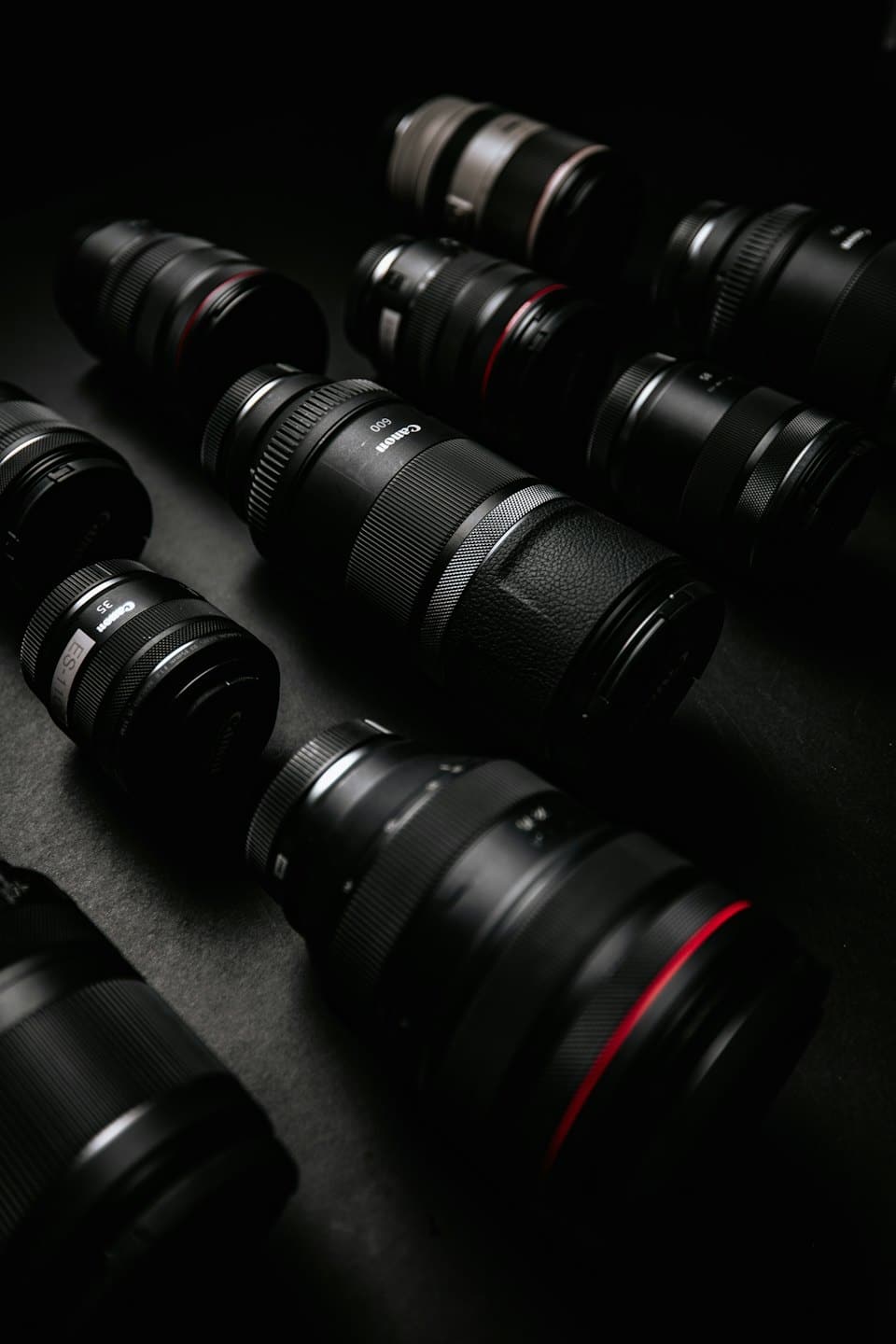 Professional camera lenses arranged on a dark surface.
