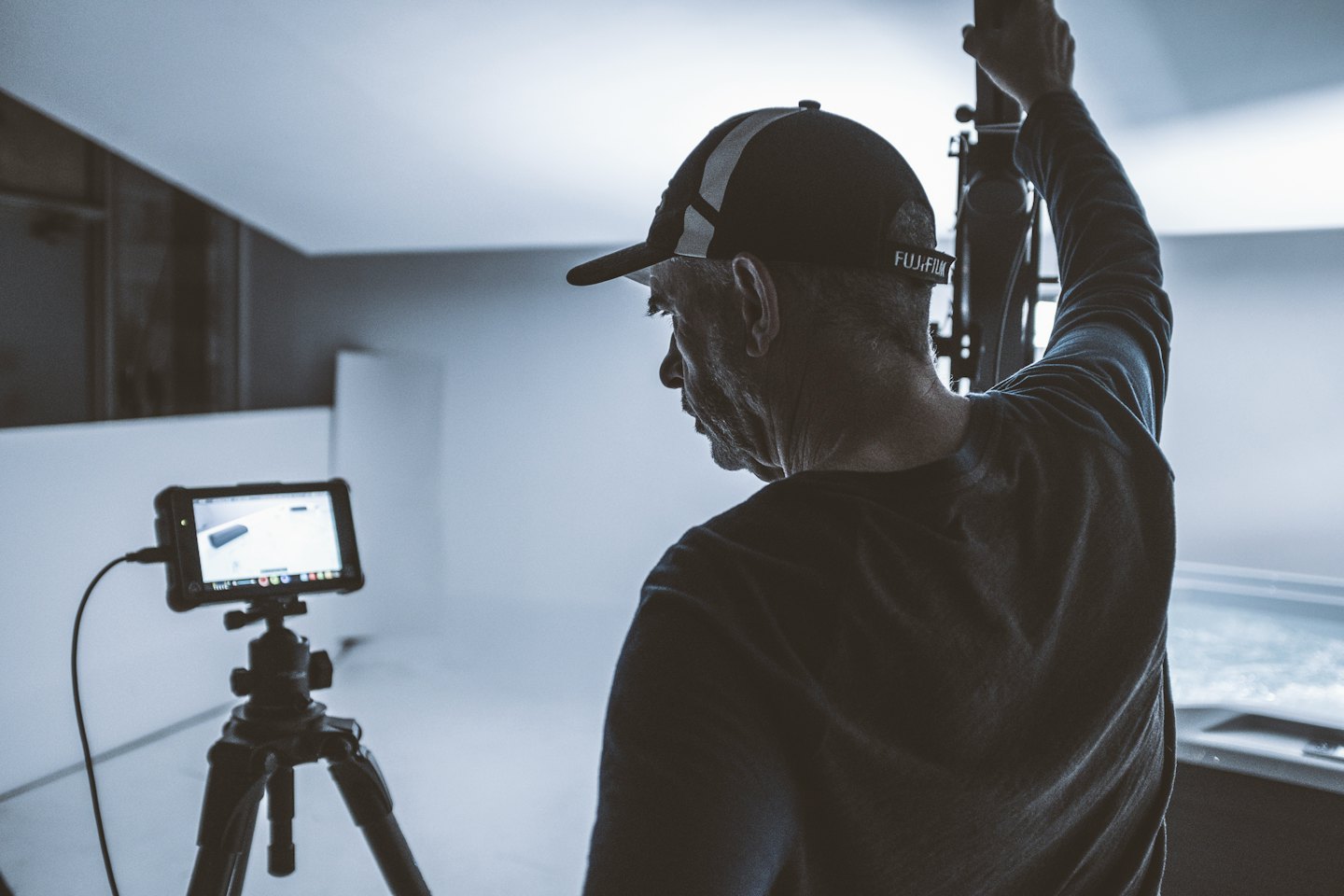 A videographer adjusts equipment while viewing a product monitor.