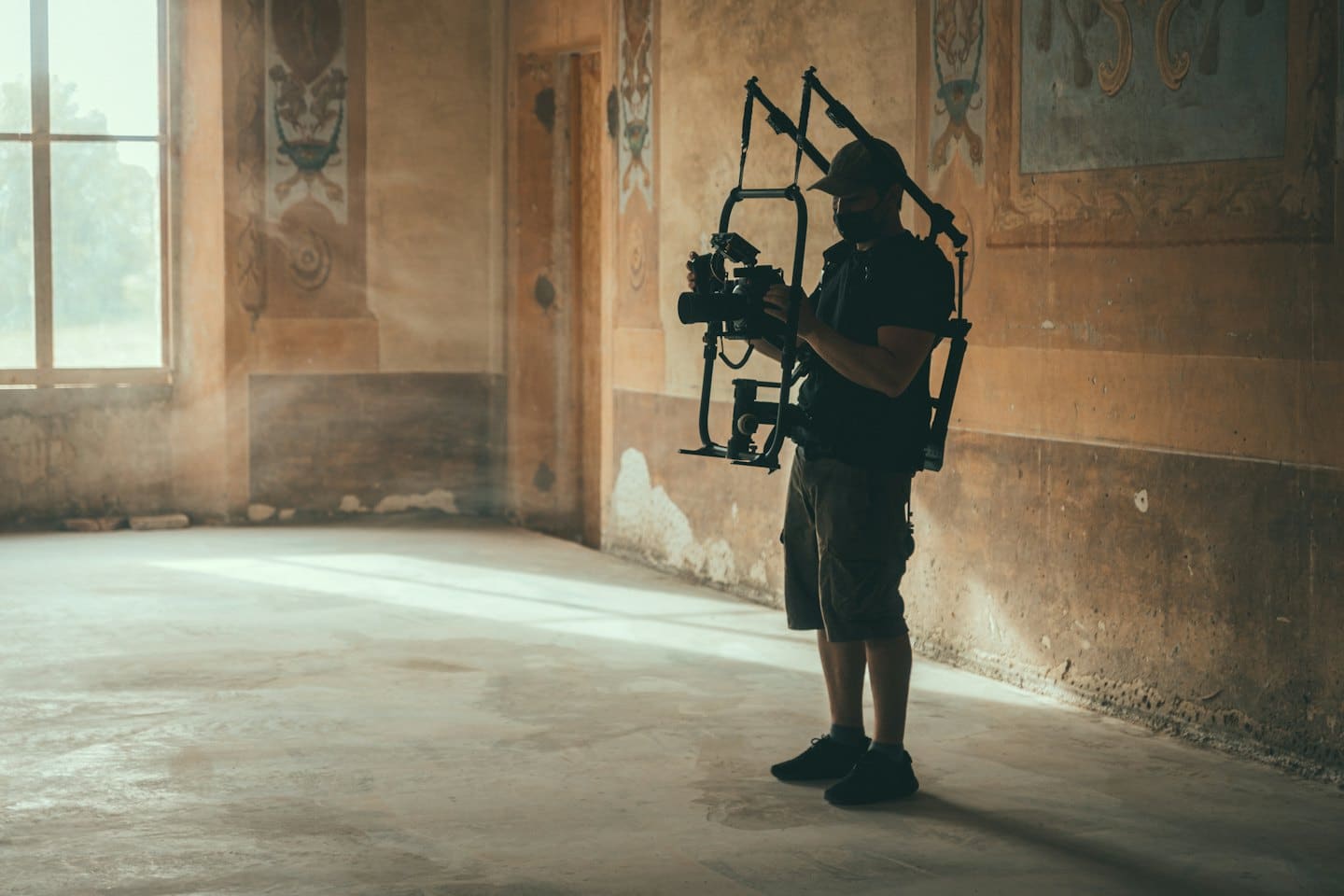 Videographer films in a dusty, sunlit abandoned room.