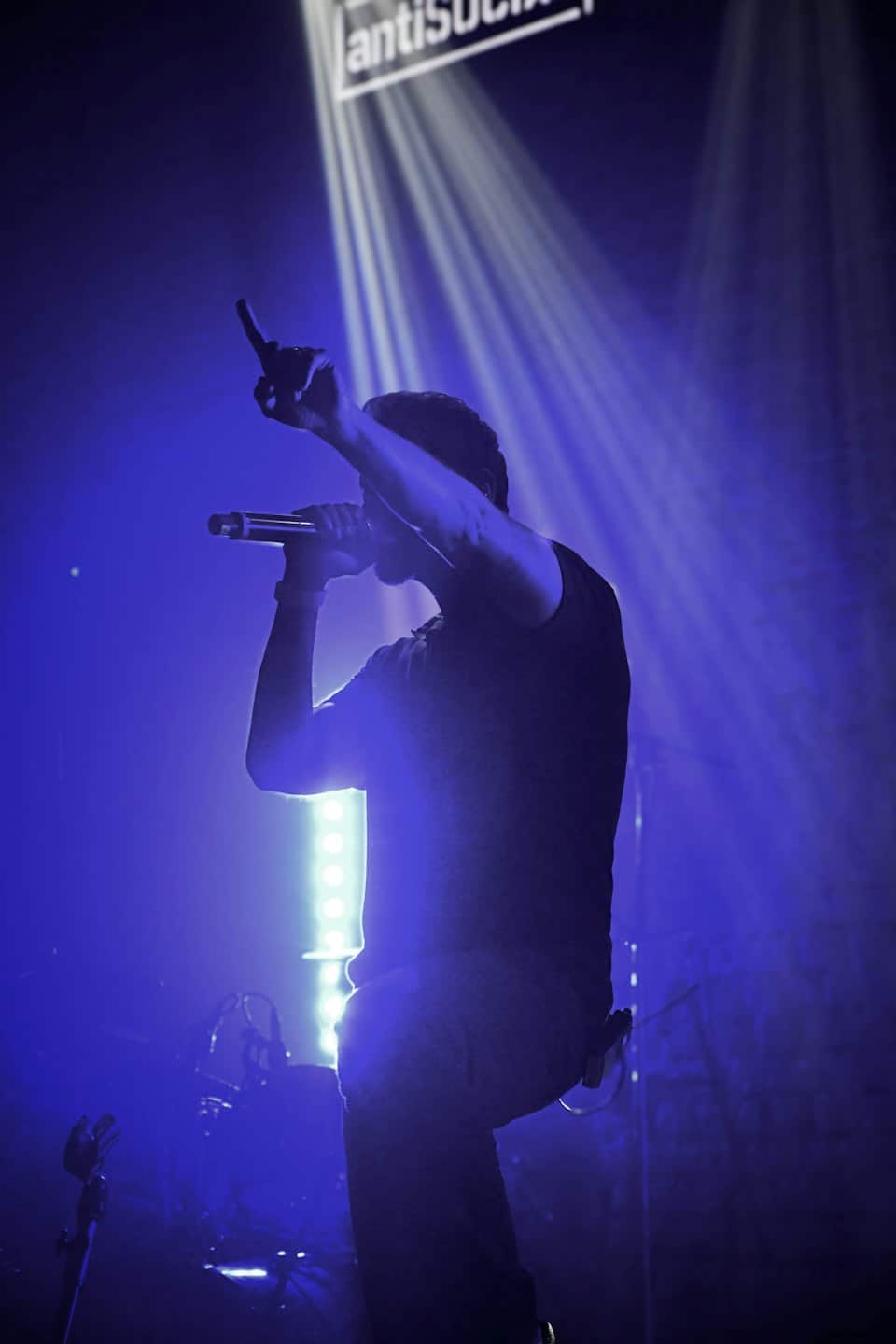 Musician singing into a microphone on a concert stage.