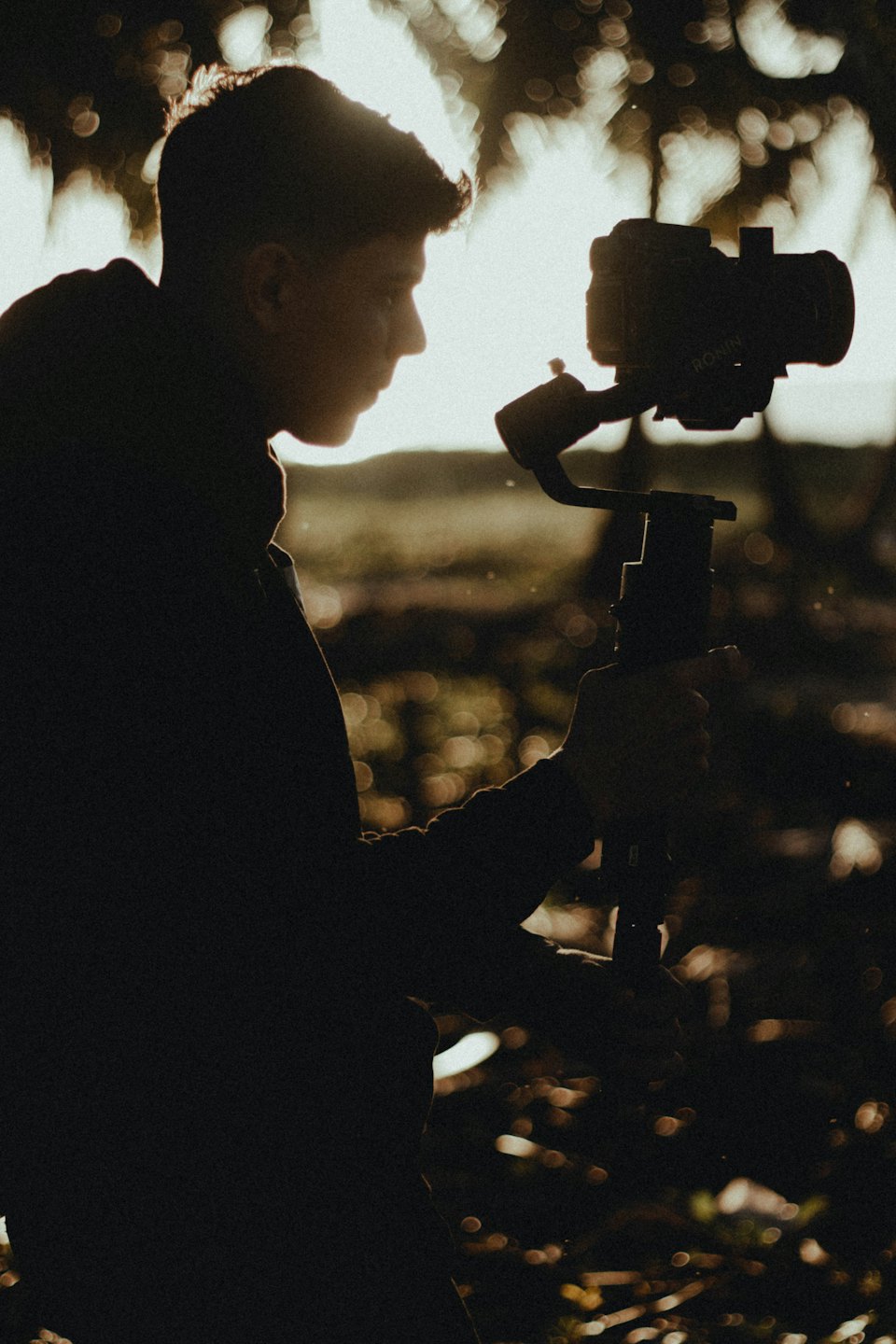 Videographer holds a gimbal mounted camera outdoors.