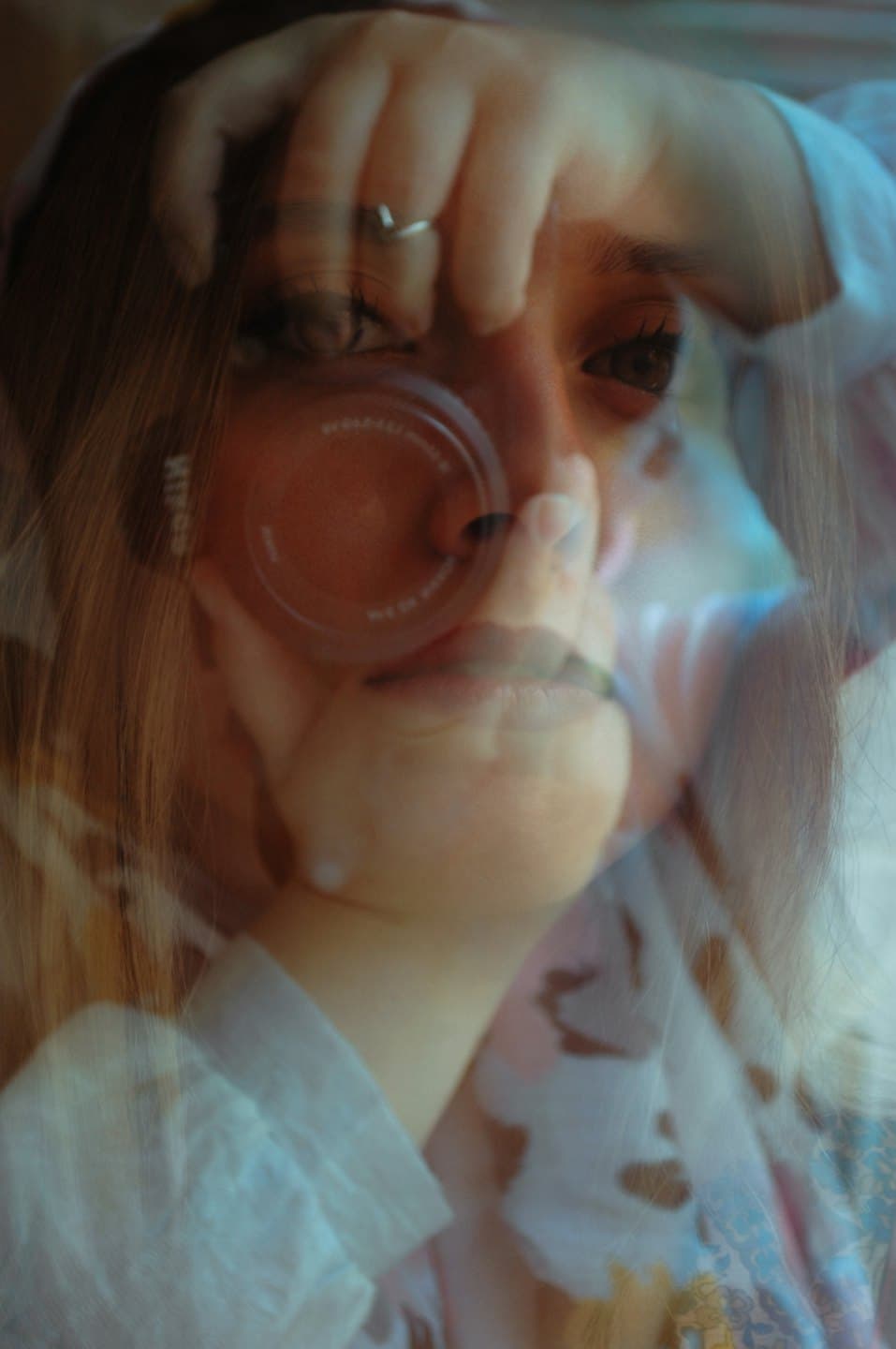 Woman looking into a camera lens with a hand on her head.